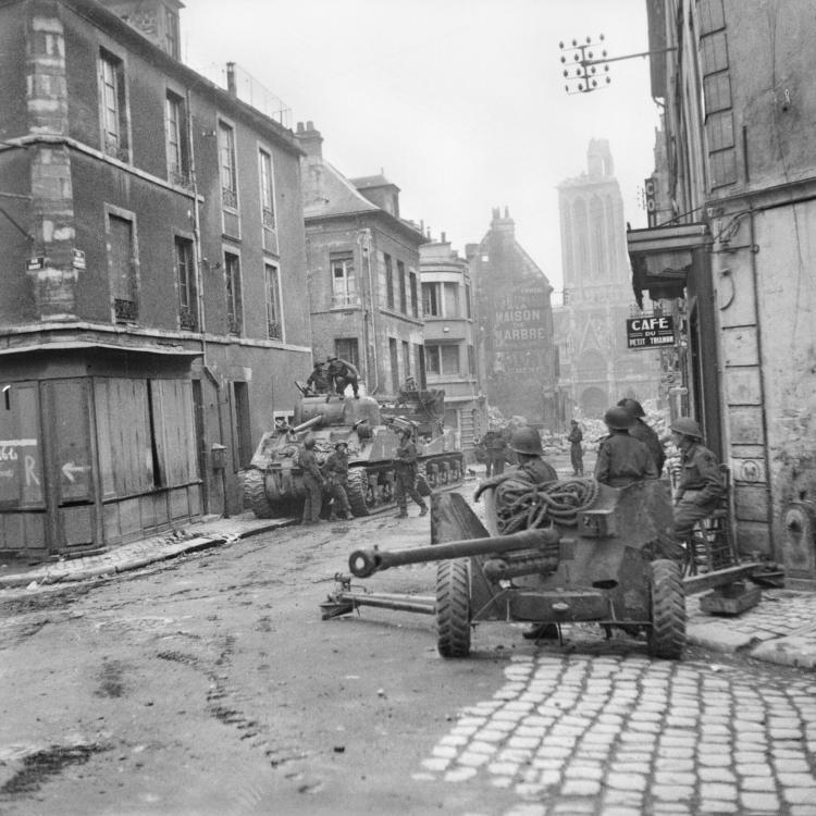 British_Sherman_tanks_and_a_6-pdr_anti-tank_gun_in_the_centre_of_Caen,_Normandy,_10_July_1944__B6924.jpg